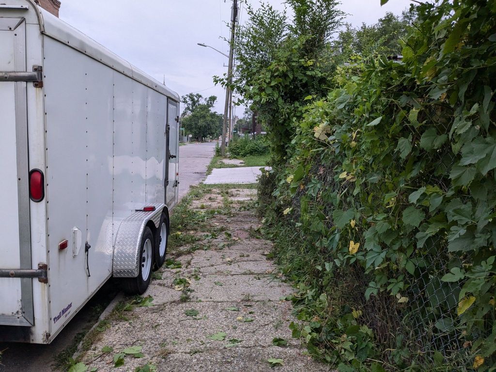 Sidewalk that was covered in sticks is now clear. Right next to a white trailer.